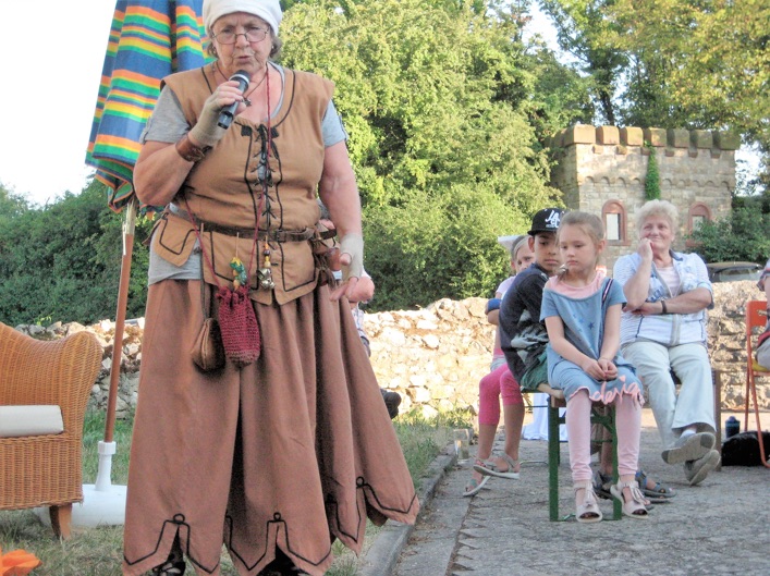 Im mittelalterlichen Gewand wanderte die Erzählerin mit Handmikro durchs Publikum, ab und an innehaltend, um die Zuhörer nach dem Titel eines Märchens zu fragen oder um sie in die Geschichten einzubeziehen. Die Anwesenden lauschten so aufmerksam, dass nur mehr der leise Wind in den Bäumen zu hören war.