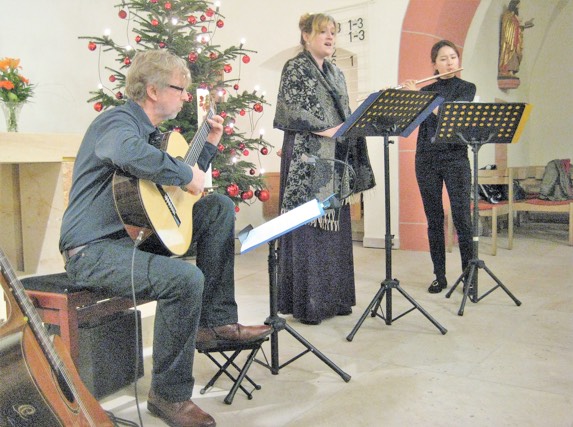 Im weihnachtlich geschmückten Altarraum konzertierten (von links nach rechts im Bild) Jürgen Zimmer (Gitarre), Heidrun Höflinger (Sopran) und Ji-Hyun Son (Querflöte). Alle drei sind Musikpädagogen aus dem Frankfurter Raum. 	           Foto: Anja Krollmann